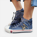 Close-up side profile of navy denim high-top trainers with dark laces, white toe cap and contrast striped sole