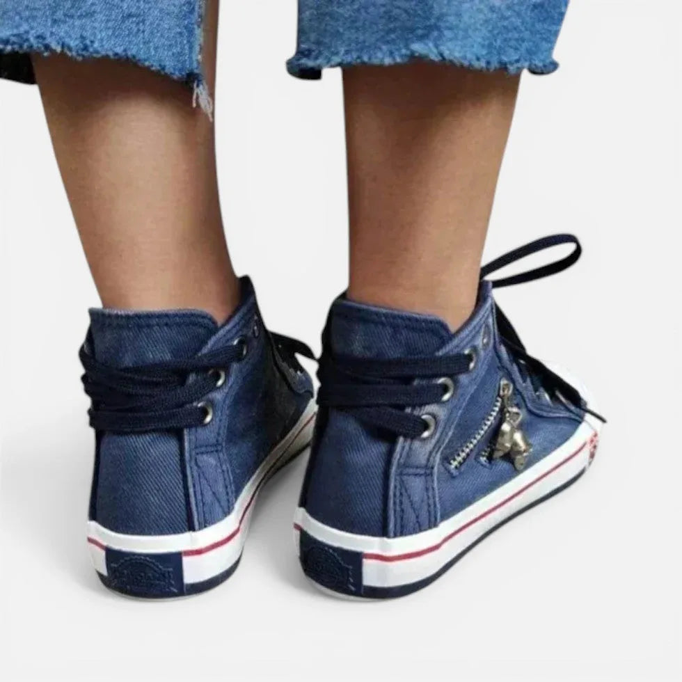 Back view of navy denim high-top trainers with tied laces and small metal charm on the side zip