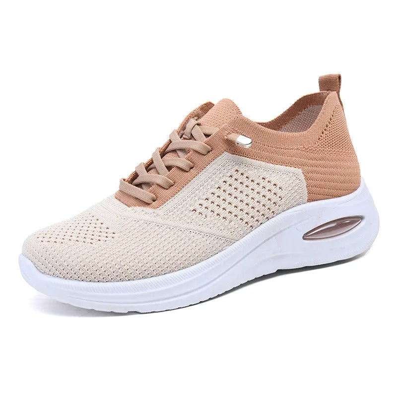 Three-quarter angled view of beige mesh trainer showing tan overlay panels, perforated toe box and white platform sole