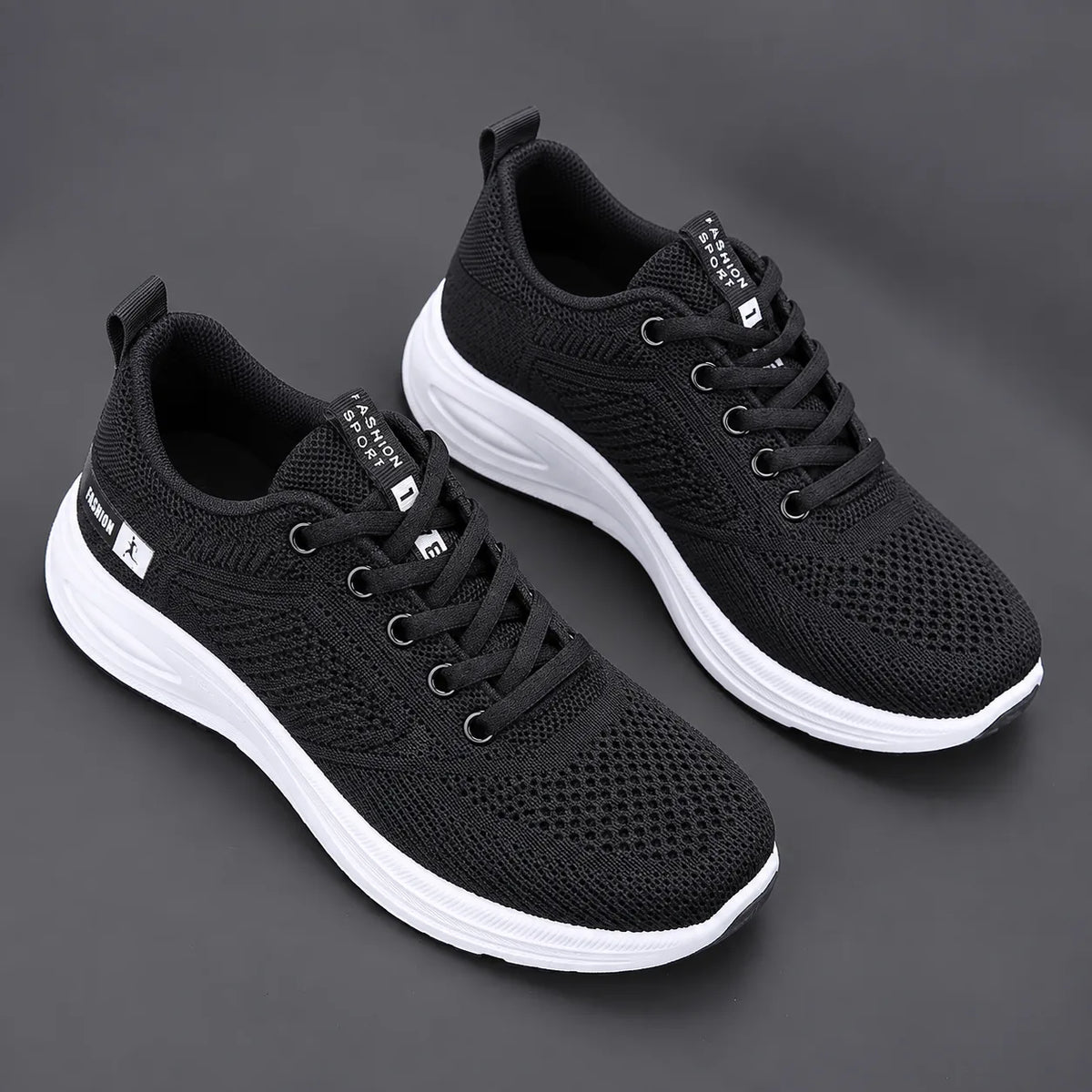 Pair of black mesh trainers with white laces, metallic eyelets and two-tone white midsole with black tread