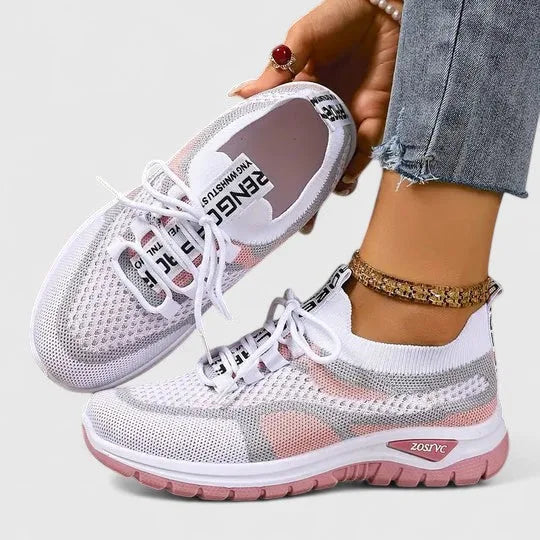 White mesh trainers with pink and grey panels and pink cushioned sole, shown from side profile on foot
