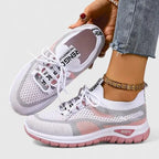 White mesh trainers with pink and grey panels and pink cushioned sole, shown from side profile on foot