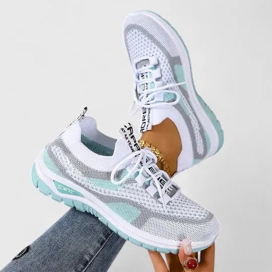 White and mint green mesh trainers with contrast green outsole, shown held up in mid-air