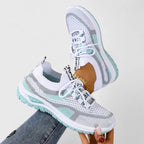 White and mint green mesh trainers with contrast green outsole, shown held up in mid-air