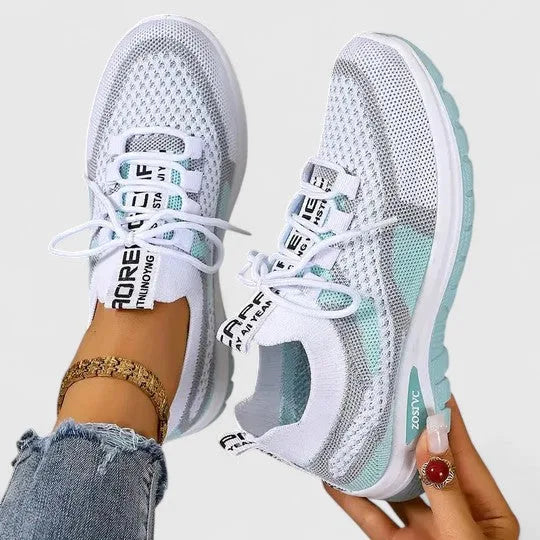 White and mint green knit trainers worn on foot with cushioned sole detail visible from the side