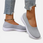 Grey knit slip-on trainer with white sole, worn on foot with cropped jeans and an anklet chain