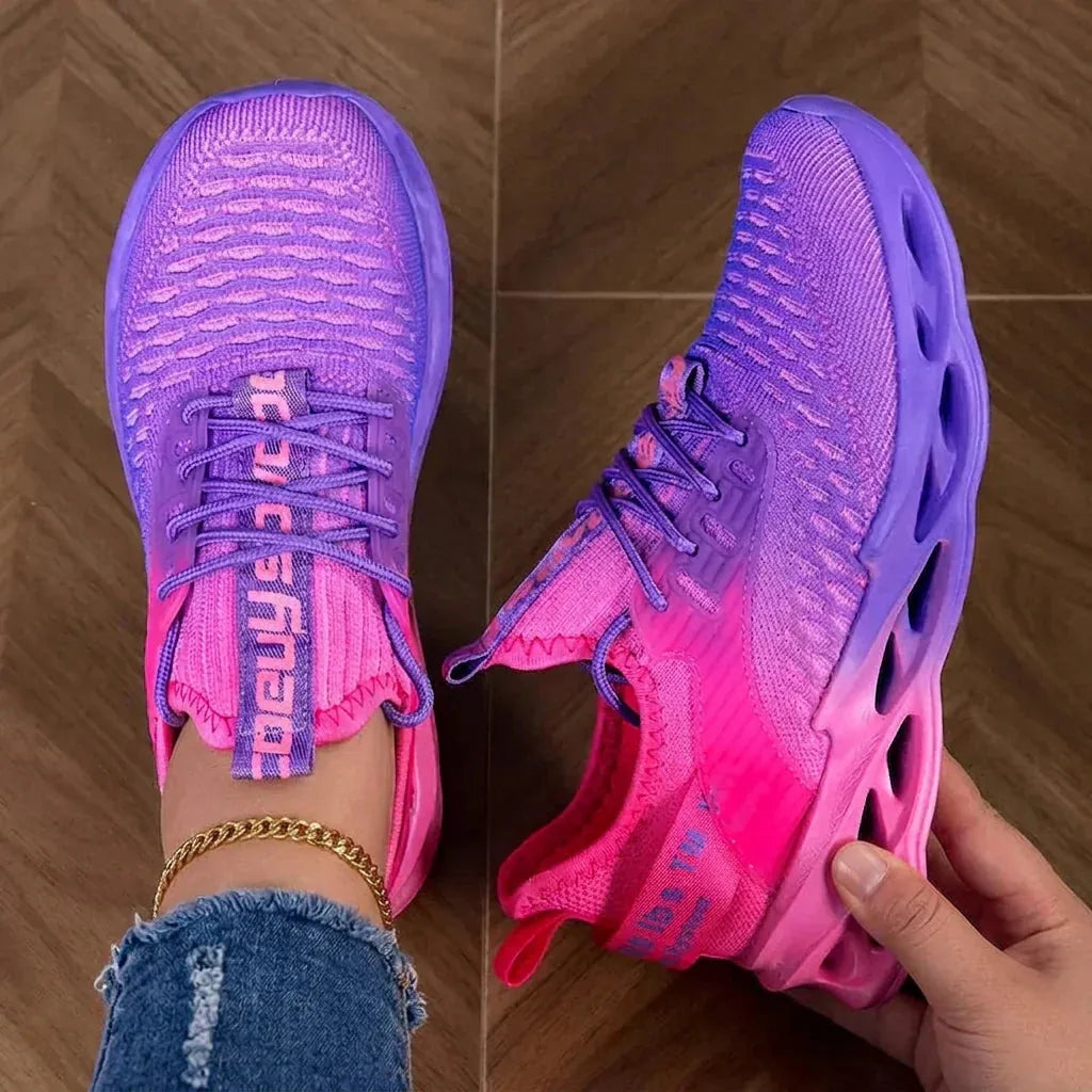 Top-down view of pink to purple gradient knit trainers with laces, worn on feet, showing cushioned curved sole