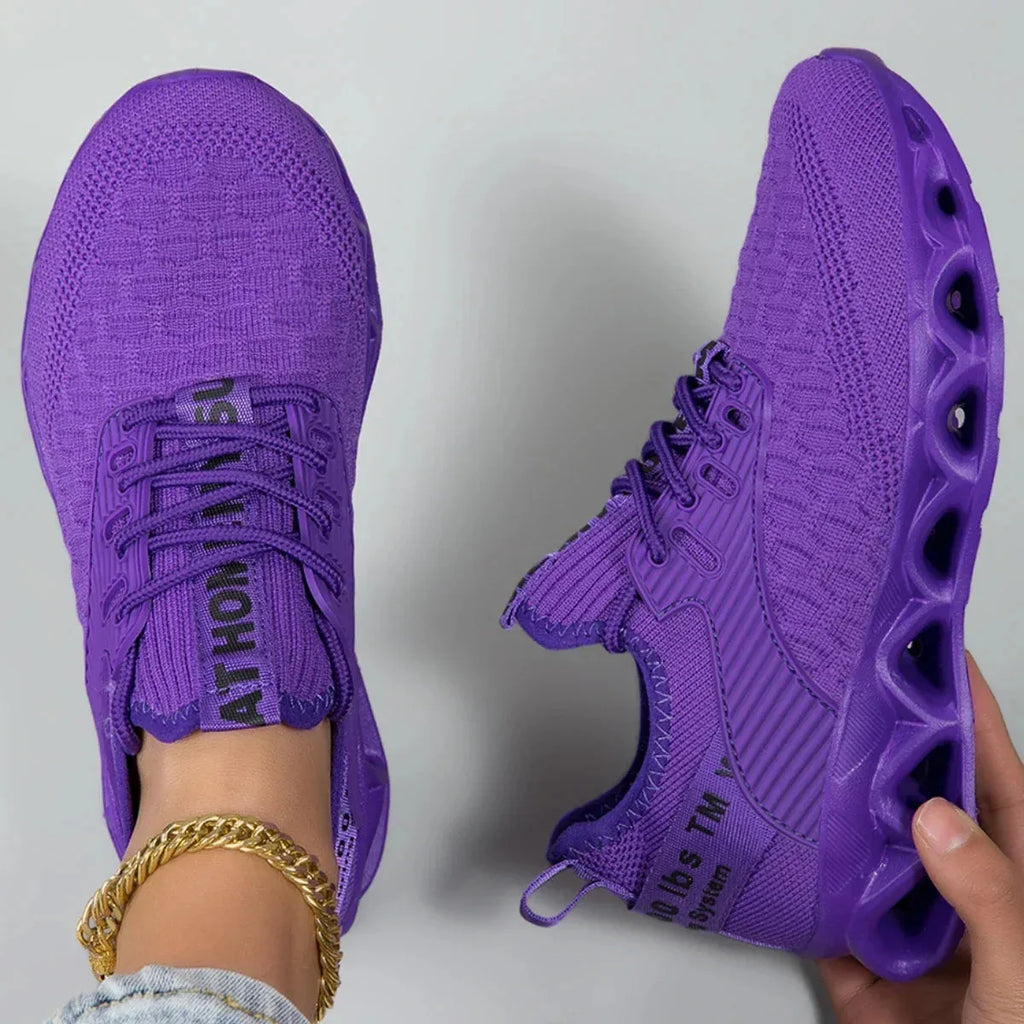 Top-down and side view of a pair of purple knit trainers showing the ribbed side panel and tunnel sole