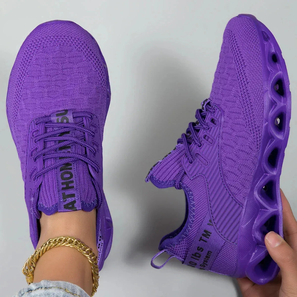 Top-down and side view of a pair of purple knit trainers showing the ribbed side panel and tunnel sole