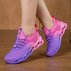 Side profile of pink and purple ombre knit trainer mid-step, highlighting the open cutout sole design
