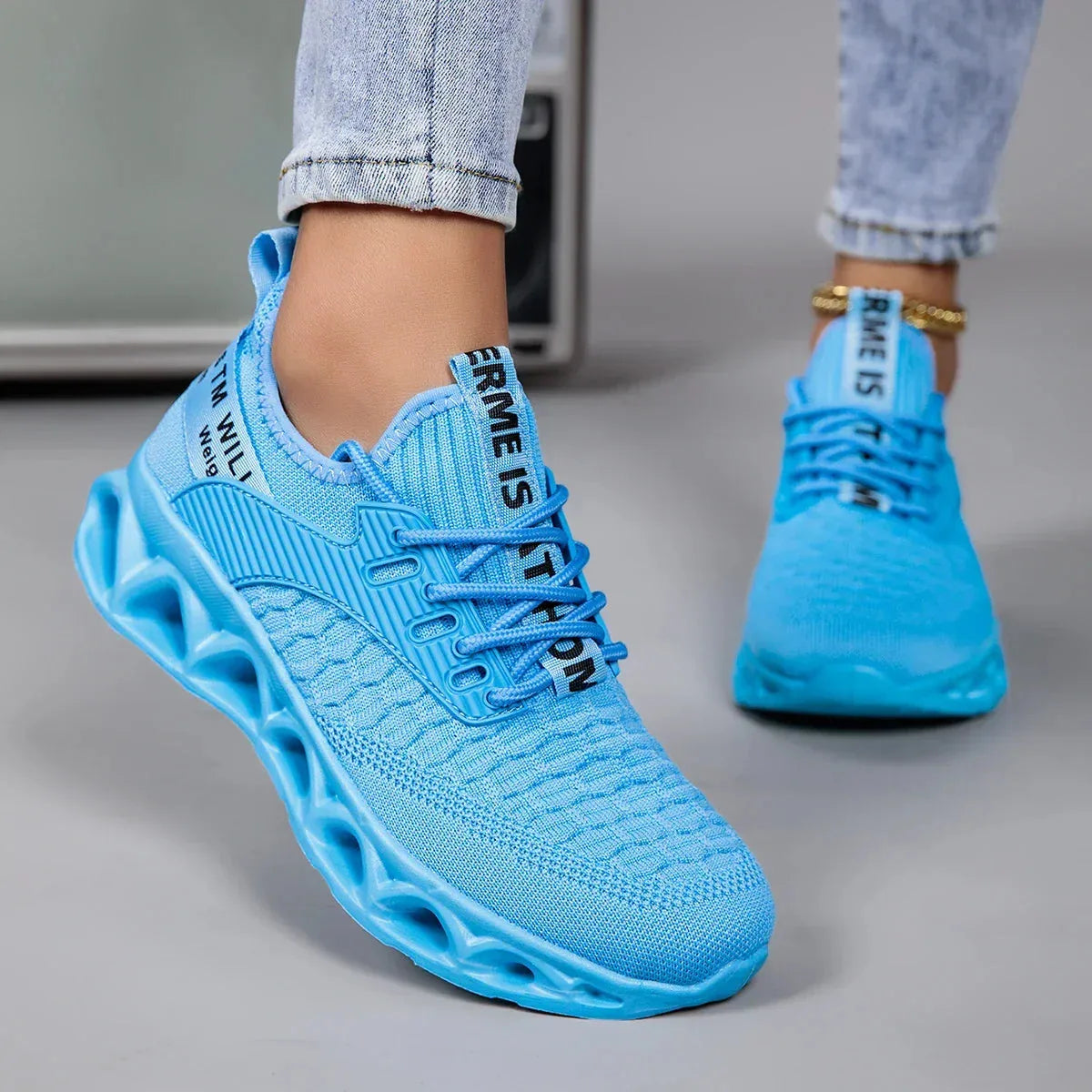 Close-up side view of a sky blue knit trainer showing the ribbed panel, laces and translucent-look sole