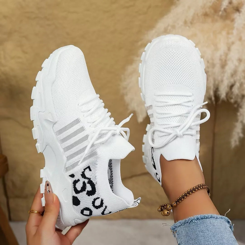 Close-up angle of cream trainers showing the textured knit upper and ridged white outsole