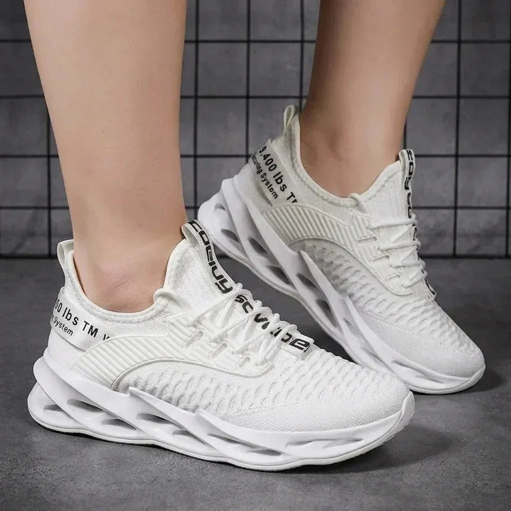 Side view of a pink to blue gradient knit trainer balanced on white wheel stands against a grey backdrop