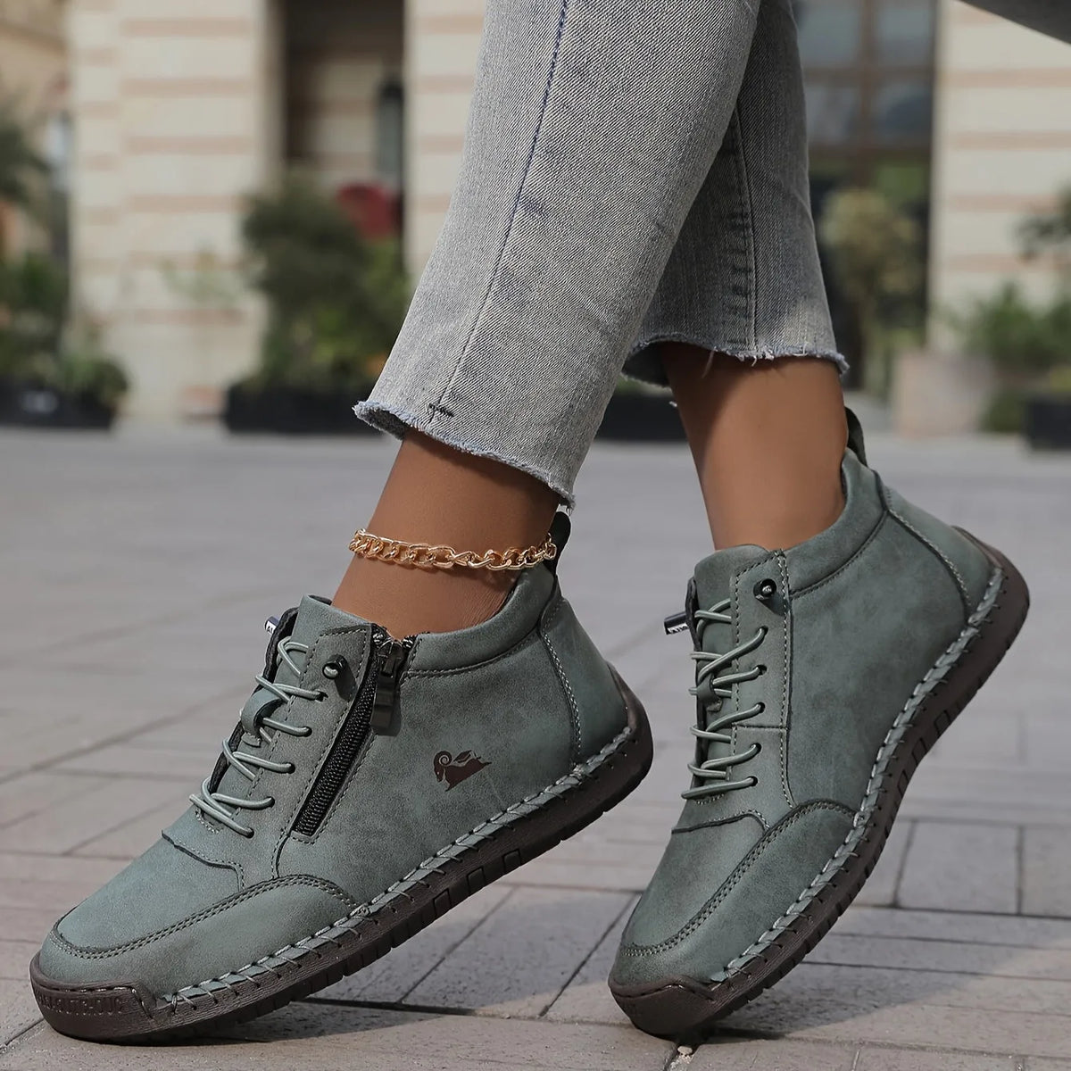 Grey suede high-top trainer with black zip pull and hand-stitched welt, worn with cropped jeans