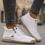 Black leather ankle sneaker with orange heel tab accent and textured rubber sole, side angle
