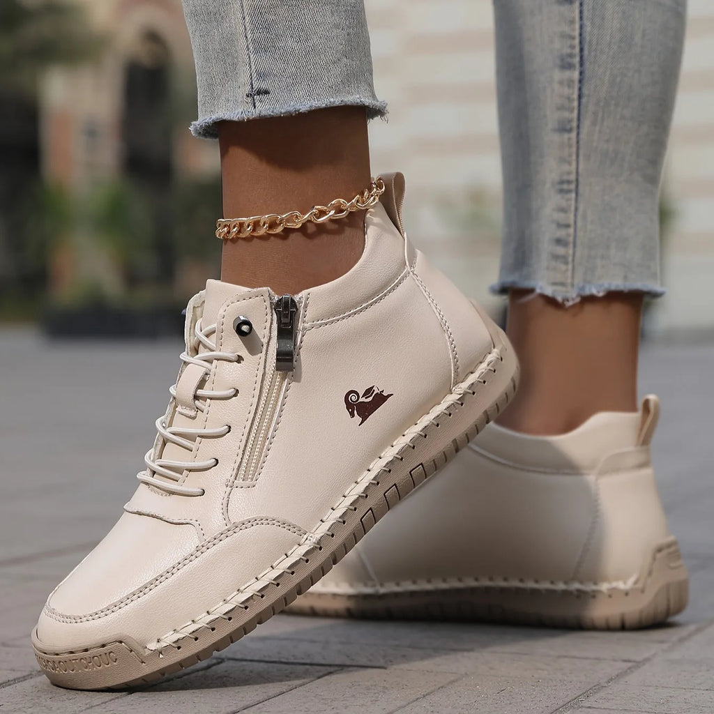 Close-up of cream leather high-top trainer with zip fastening, embossed ram logo and hand-stitched sole detail