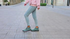 Grey suede ankle trainer lifted mid-stride, showing the ribbed sole and heel pull loop