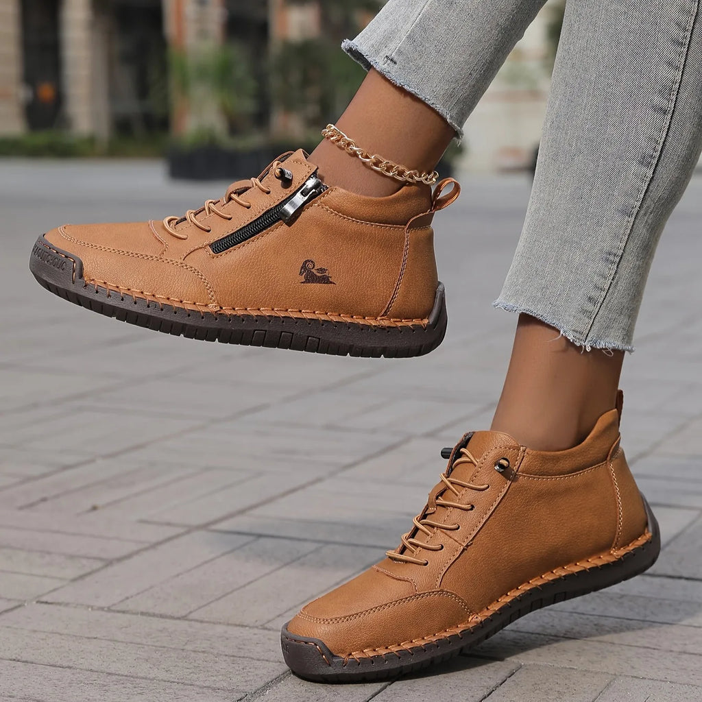 Angled view of camel brown leather ankle sneaker mid-stride, showing zip, laces and ram logo detail