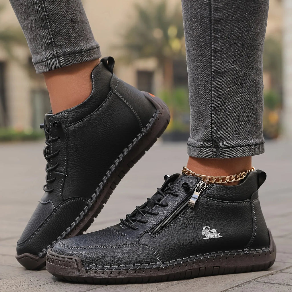 Black leather high-top trainer with silver zip pull and hand-stitched detailing shown in walking motion