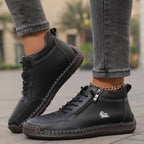 Black leather high-top trainer with silver zip pull and hand-stitched detailing shown in walking motion
