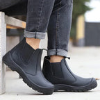 Close-up of black Chelsea boots worn with rolled jeans while seated, highlighting the ankle fit and pull tabs