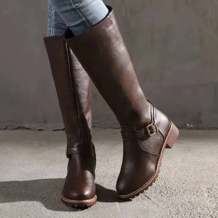 Close-up side view of dark brown leather boot highlighting buckle strap and stitched leather panels