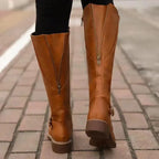 Back view of tan brown boots on cobblestone street showing centre-back zip detail