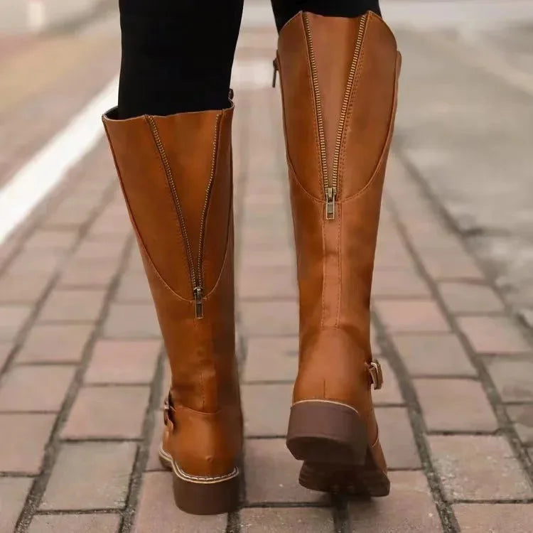 Back view of tan brown boots on cobblestone street showing centre-back zip detail