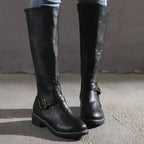Front standing view of black leather knee-high boots showing buckle strap and round toe shape
