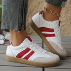 Side view of red and white retro trainers with striped panel and gum sole, worn with cropped denim and gold anklet