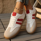 Close-up of red and white trainer toe box showing suede panelling, white laces and textured gum outsole