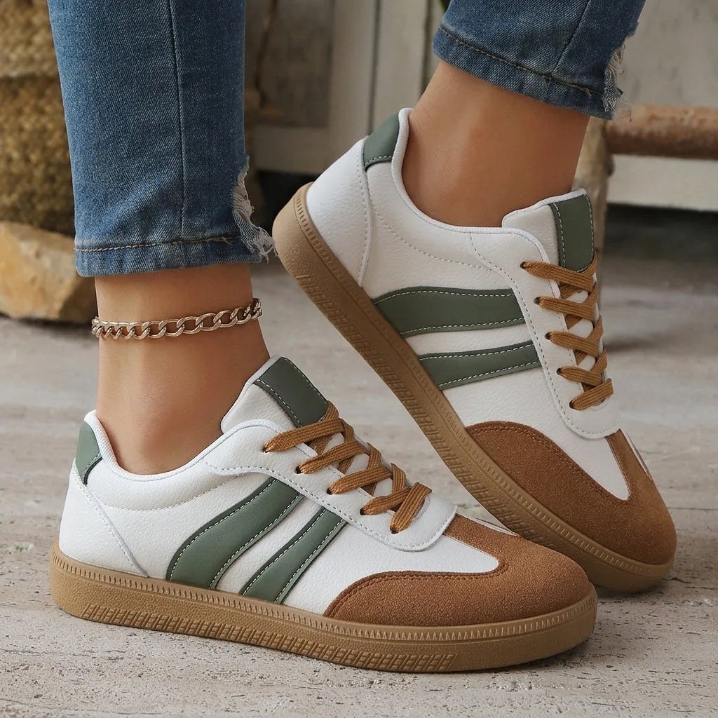 Angled close-up of the red heel tab and double stripe detail on a white leather trainer