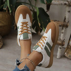 Close-up front view of green striped trainers showing tan lace-up detail and gum sole tread