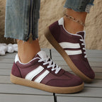 Top-down view of green and white trainers with tan toe panels, feet crossed and resting on a ledge