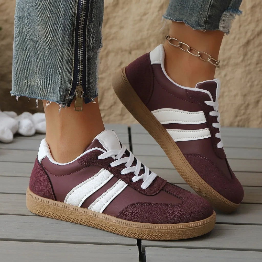 Top-down view of green and white trainers with tan toe panels, feet crossed and resting on a ledge