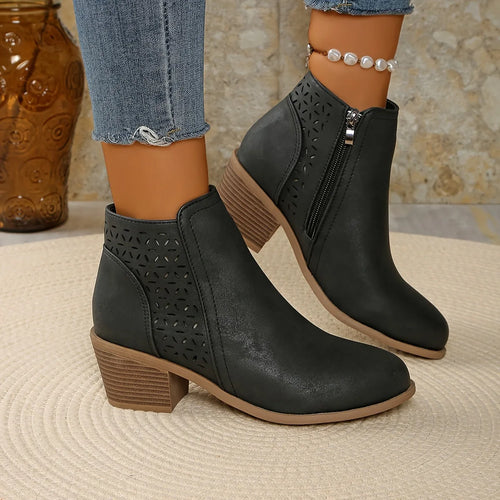 Side view of black perforated ankle boots with stacked block heel worn with cropped jeans and pearl anklet