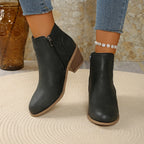 Model walking in black perforated ankle boots, front view showing rounded toe and low block heel