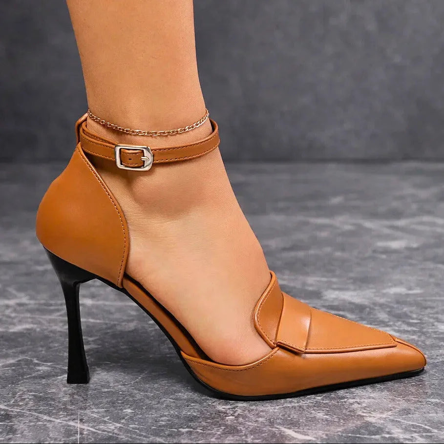 Side profile of tan pointed-toe court heel showing folded vamp detail and slim spool heel