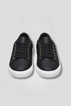 Front view of black quilted lace-up trainers with white soles, shown together facing forward