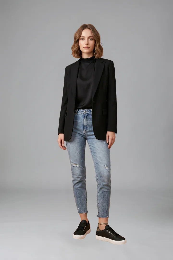 Model wearing black quilted trainers with a black blazer, satin top and ripped mom jeans