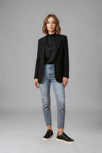 Model wearing black quilted trainers with a black blazer, satin top and ripped mom jeans