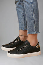 Side view of black trainers showing quilted panel, gold eyelets and metallic gold heel tab