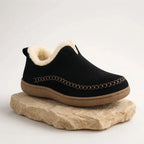 Side view of a black suede slip-on boot with cream shearling lining and contrast stitched moccasin seam