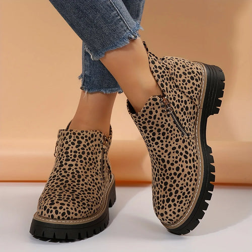Side profile of leopard print ankle boot with gold side zip and chunky lugged black platform sole, worn crossed at the ankle