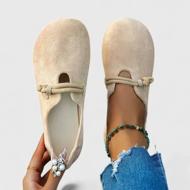 Overhead view of beige suede slip-on flats with knotted rope strap detail across the instep
