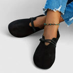 Side profile of black suede slip-on flats worn with rolled jeans, showing the cut-out vamp design