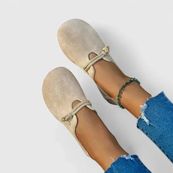Pair of beige suede slip-on flats shown from above, highlighting the round toe and soft texture