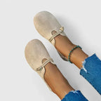 Pair of beige suede slip-on flats shown from above, highlighting the round toe and soft texture