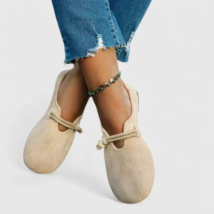 Front angle of beige suede flats worn on feet, showing the rope strap and relaxed round toe shape