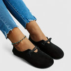 Close-up side view of black suede flats worn with cropped denim, showing the slip-on heel and sole